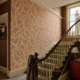 Orange geometric wallpaper in a stairwell, Twisted Geo Ginger by OHPOPSI, with joinery painted in Poppy